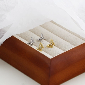 Gros plan de boucles d'oreilles papillon en or et argent avec zircons sur velours beige
