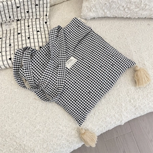 Close-up of black and white plaid canvas tote bag with tassel trim and woven label