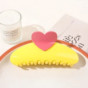 Detail of sweet heart hair claw clip in yellow with pink heart on a decorative tray