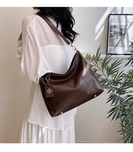 Macro shot of dark brown tote bag with wide strap and metallic protective bottom feet
