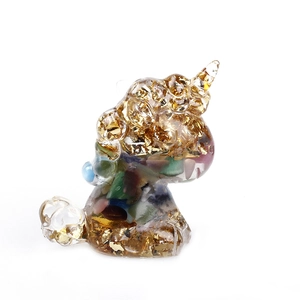 Glittering resin unicorn figurine with colorful crystals and gold leaf on white background