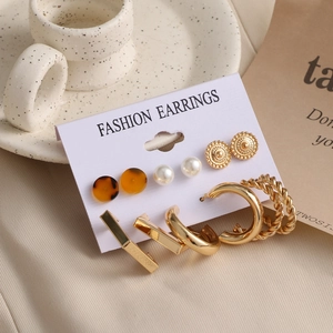 Detailed macro view of 6-pair gold earring set with pearls and resin on a decorative card