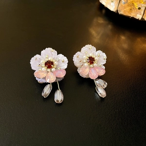 Purple flower earrings with pearls and gems on black leather background