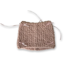 Pink knit beanie hat with cat ears and ribbon bows on a clean white background