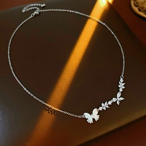 Vue détaillée du collier argenté avec pendentif papillon en zircon et pompon élégant
