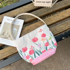 Detail of floral bucket canvas bag with pink tulip illustration on a wooden bench