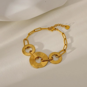 Detail of gold hammer-textured rings and paperclip chain bracelet with heart charm