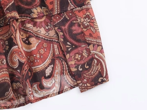 Gros plan sur le tissu mousseline à motif paisley rouge foncé et volants superposés