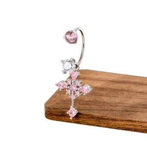 Bauchpiercing-Kreuz mit rosa Zirkonia und poliertem Chirurgenstahl auf Holzblock