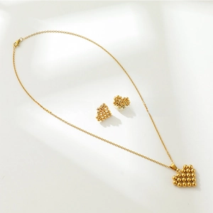 Détail d'un ensemble collier et boucles d'oreilles cœur au motif perlé doré