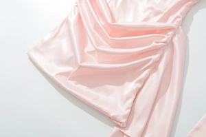 Détail de robe en satin rose montrant des plis élégants et une texture soyeuse