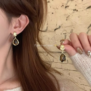 Detailed close-up of vintage golden tiger's eye stone teardrop earrings on a model