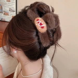 Detailed view of coffee brown plush bread hair claw clip worn on a low bun hairstyle