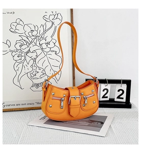 Detail of orange motorcycle hobo bag featuring silver rivets and decorative zippers