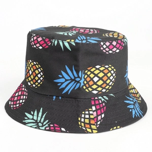 Detailed close-up of vibrant pineapple print on black cotton bucket hat fabric