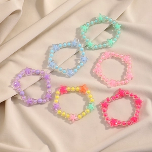 Detail of colorful acrylic star beaded bracelets in various candy colors on beige fabric