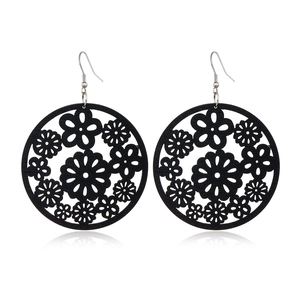 Detailed close-up of black hollowed-out wooden earrings with intricate floral patterns