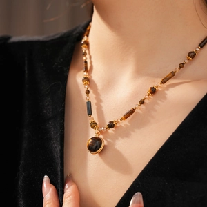 Close-up of tiger eye beaded necklace with a round golden pendant on a model neck