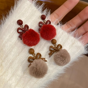 Dettaglio di orecchini a fiocco con palline di peluche rosso e marrone per l'autunno