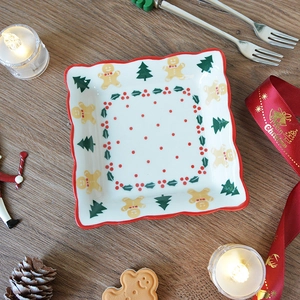 Christmas ceramic plate with gingerbread man and pine tree motif in wavy red rim design