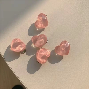 Close-up of five glossy pink resin heart-shaped hair clips on a light beige surface