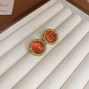 Macro detail of vintage resin heart earrings with golden diamond pattern borders in a box
