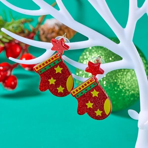 Close-up of red glitter acrylic Christmas glove earrings with star detail on branch