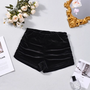Detailed view of black velvet high-waisted shorts with side ruffles and soft texture