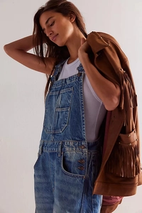 Detail of denim dungarees with front pocket and jacket featuring long brown tassels