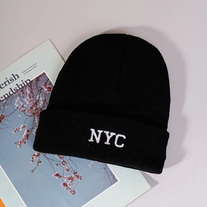 Close-up of white NYC embroidery on a black knitted beanie with a folded cuff detail
