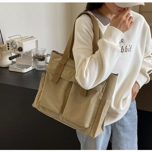 Close-up of khaki canvas tote bag featuring brown straps and multiple storage pockets