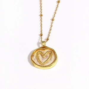 Detail of gold necklace with irregular round heart pendant and purple glitter accents