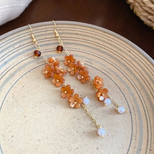 Detailed close-up of resin flower and pearl tassel earrings on a ceramic dish
