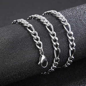 Macro shot of silver titanium Figaro chain necklace with lobster clasp on black cylinder