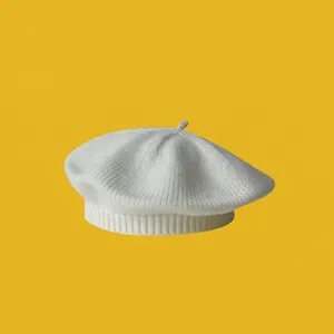 Close-up of white knitted baby beret showing fine ribbed texture and decorative top stem