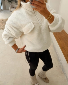Detail of white fleece sweatshirt featuring half-zip collar and front flap pocket
