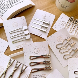 Close-up of three silver hollow metal hair clips in heart and geometric shapes for women