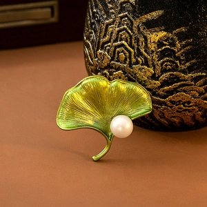 Detailed view of green and gold ginkgo leaf brooch with elegant white pearl detail