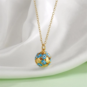 Close-up of golden sphere pendant with blue evil eye charms on silk background