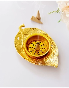 Detailed view of leaf-shaped golden incense burner with internal holder and smoke