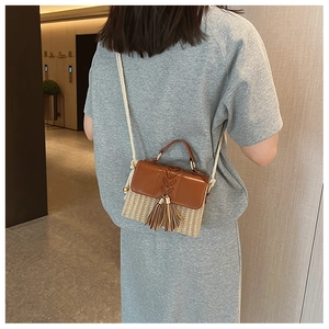 Detail of brown PU leather and straw woven crossbody bag with stylish tassel accents