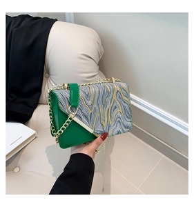 Detail of green and grey contrast handbag with gold chain strap and marble pattern