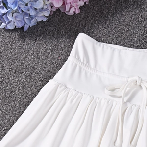 Detail of white mini skirt with adjustable drawstring waist and pleated silky fabric