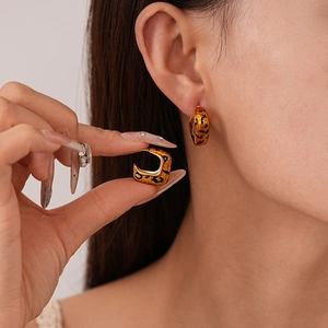 Detailed close-up of geometric leopard print earrings with gold plating on model ear