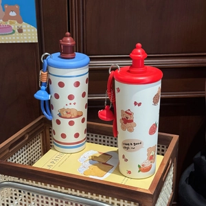 Detailed view of cute cartoon bear thermos cups in blue and red on a rustic wooden tray