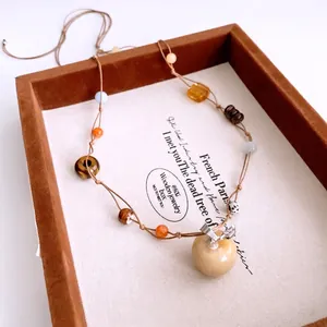 Tiger eye stone apple pendant necklace with ethnic beaded cord in a jewelry tray