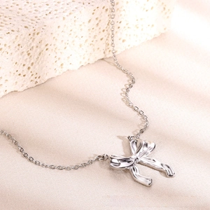 Close-up of silver bow pendant necklace on textured fabric with decorative stone