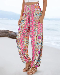 Close-up of bohemian pink high-waisted floral pants on a beach with sea backdrop