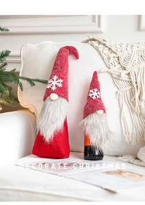 Detail of red gnome wine bottle cover with snowflake pattern and plush grey beard decoration
