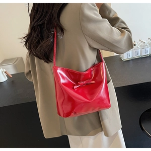 Detail of red glossy shoulder bag with a bow decoration on a minimalist model shot